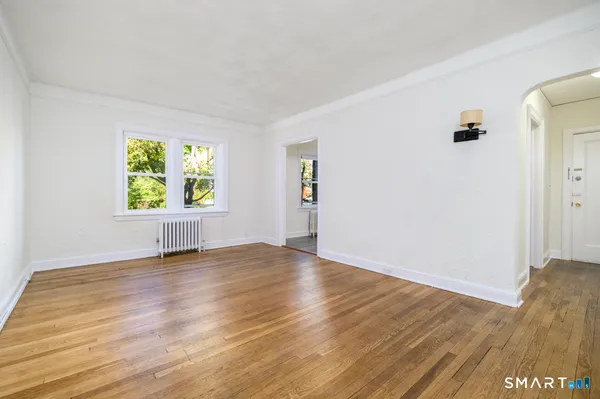 a view of an empty room with window and wooden floor