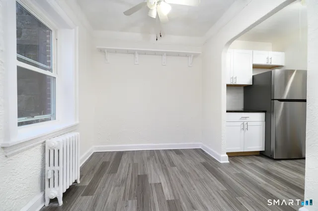 a view of a kitchen with a refrigerator a ceiling fan and wooden floor