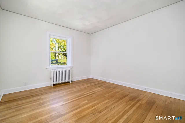 a view of empty room with window and wooden floor