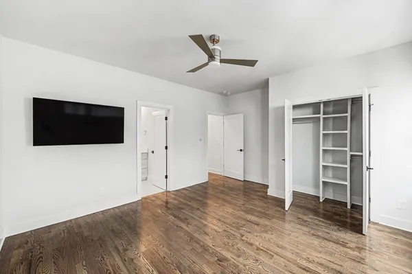 a view of empty room with wooden floor and fan