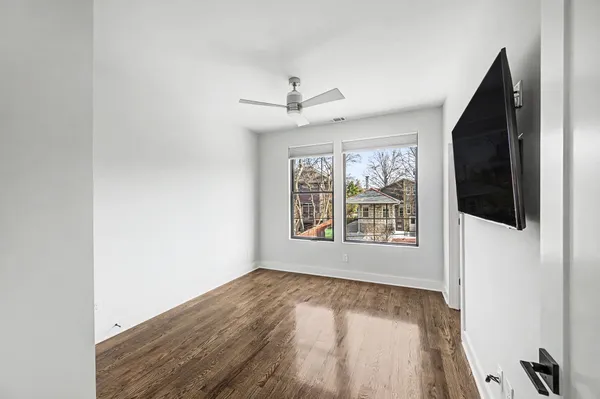 an empty room with chandelier fan and windows