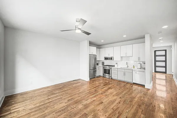 a open kitchen with kitchen island a stove a refrigerator cabinets and wooden floor