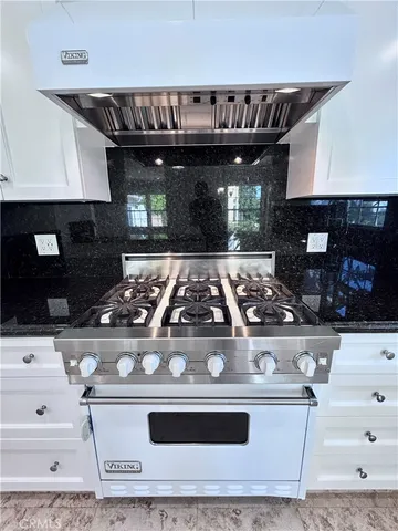 a view of an empty room with window wooden floor and kitchen view