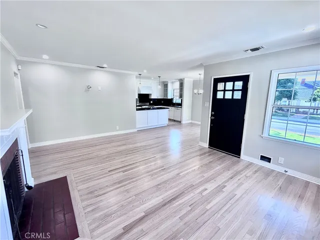 a view of an empty room with wooden floor fireplace and a window