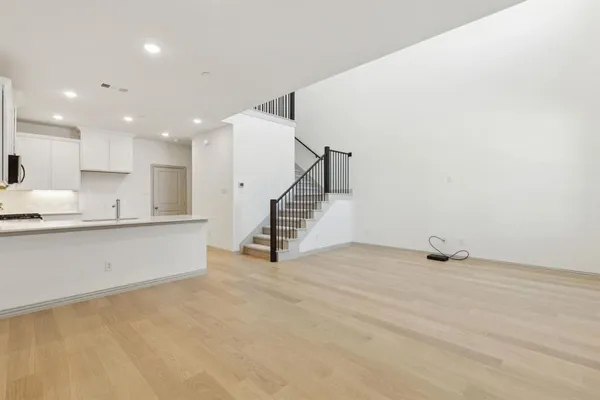 a view of an empty room with kitchen view and a window