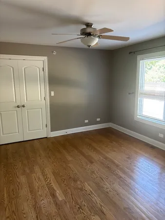 an empty room with wooden floor fan and windows