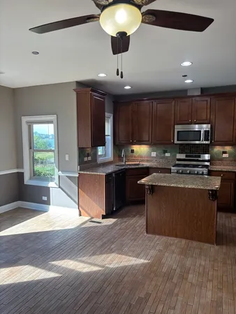 a kitchen with kitchen island granite countertop a sink cabinets and stainless steel appliances