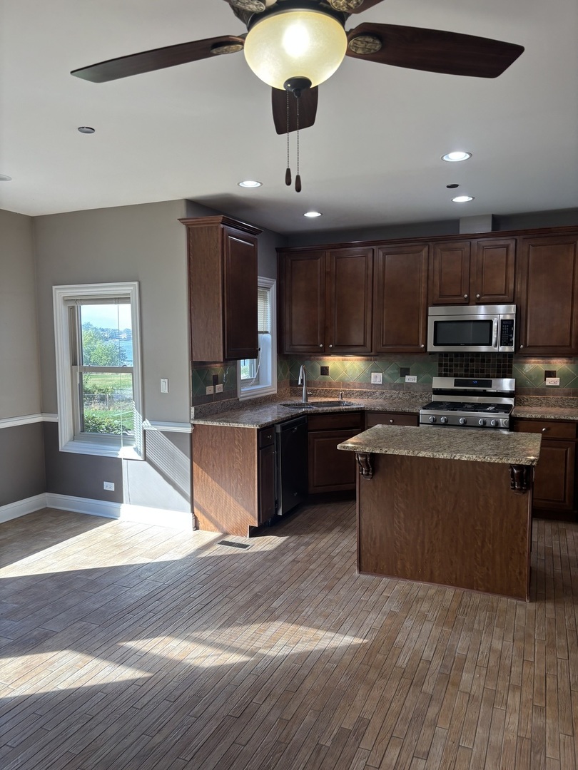 40 Mischa Court, Unit 100 Lake Zurich, IL 60047 - Photo 7 of 36 a kitchen with kitchen island granite countertop a sink cabinets and stainless steel appliances