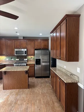 a kitchen with kitchen island granite countertop wooden cabinets a refrigerator and a sink