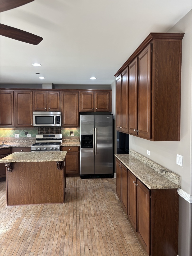 40 Mischa Court, Unit 100 Lake Zurich, IL 60047 - Photo 8 of 36 a kitchen with kitchen island granite countertop wooden cabinets a refrigerator and a sink