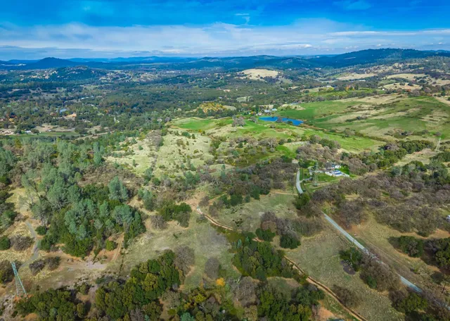 an aerial view of residential houses with outdoor space and trees