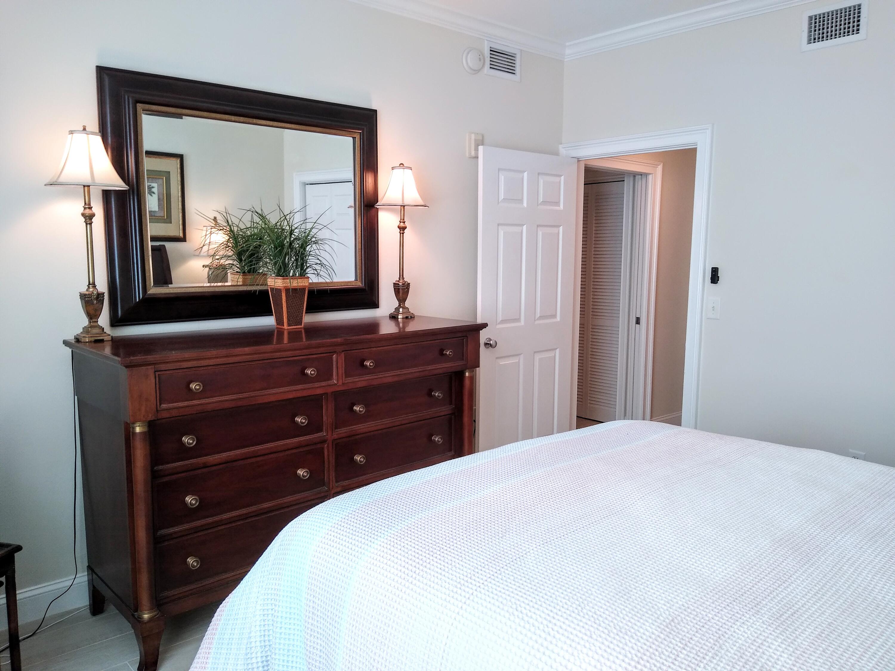 806 East Windward Way, Unit 410 Lantana, FL 33462 - Photo 19 of 33 a bedroom with a bed and a mirror on dresser