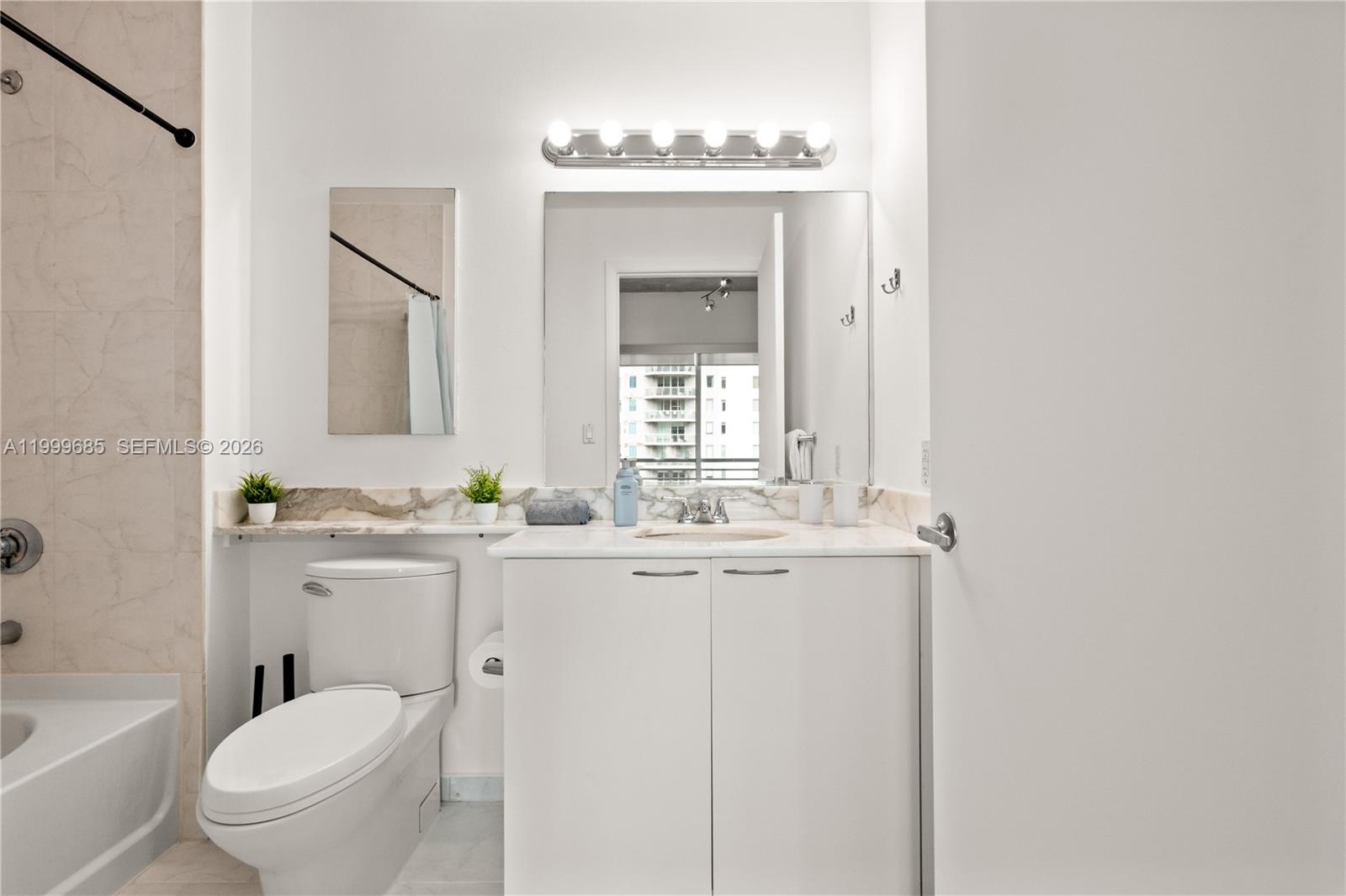 234 Northeast 3rd Street, Unit 1704 Miami, FL 33132 - Photo 28 of 35 a bathroom with a granite countertop toilet a sink and a mirror
