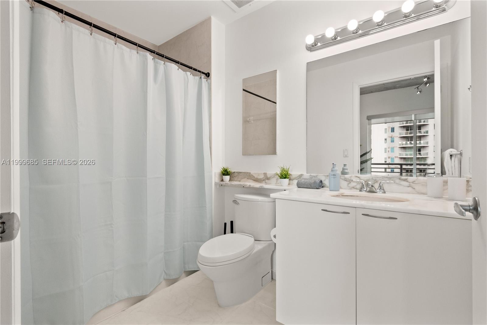 234 Northeast 3rd Street, Unit 1704 Miami, FL 33132 - Photo 29 of 35 a bathroom with a toilet a sink and a mirror