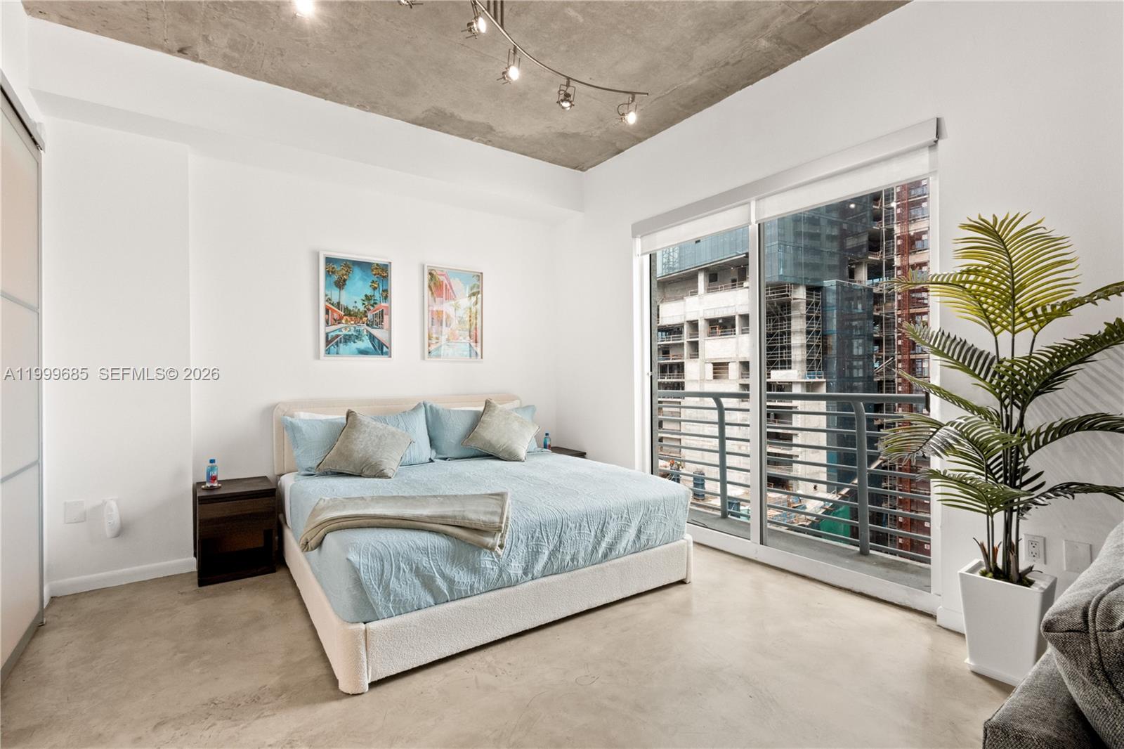 234 Northeast 3rd Street, Unit 1704 Miami, FL 33132 - Photo 8 of 35 a bedroom with a bed lamp and paintings on the wall