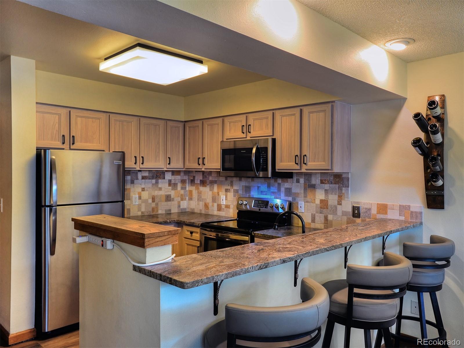 1680 Ranch Road, Unit 203 Steamboat Springs, CO 80487 - Photo 4 of 25 a kitchen with stainless steel appliances granite countertop a sink refrigerator and microwave