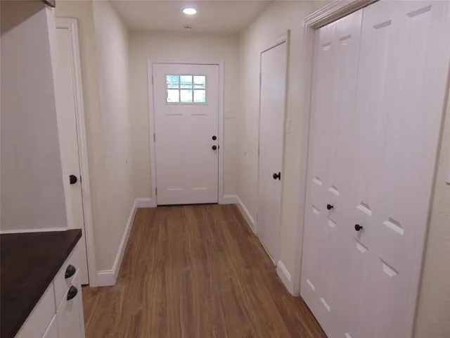 a view of a hallway with wooden floor and a bathroom