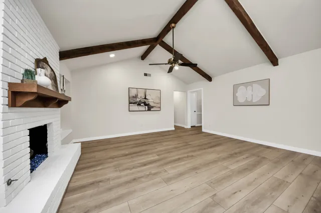a view of empty room with wooden floor and fireplace