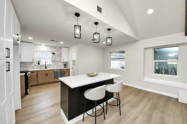 a kitchen with a dining table chairs cabinets and wooden floor