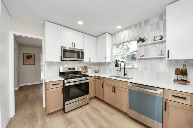 a kitchen with stainless steel appliances granite countertop a stove a sink and a microwave