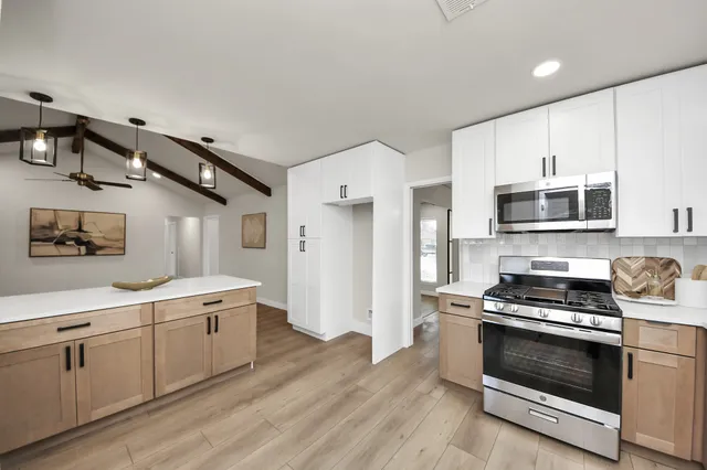 a kitchen with stainless steel appliances a stove microwave and sink