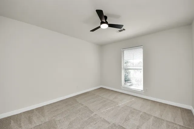 an empty room with windows and fan