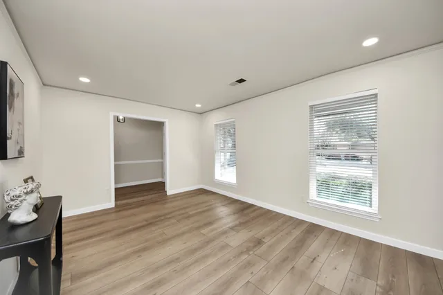 a view of an empty room with wooden floor and a window