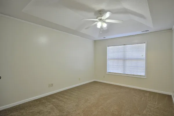 an empty room with a chandelier fan and windows
