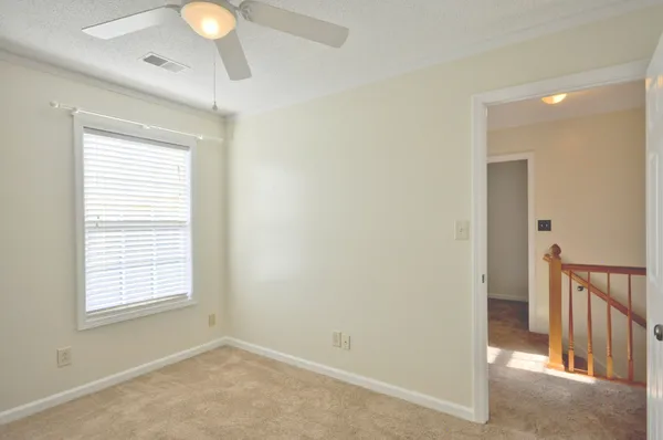 a view of an empty room with window and a chandelier fan