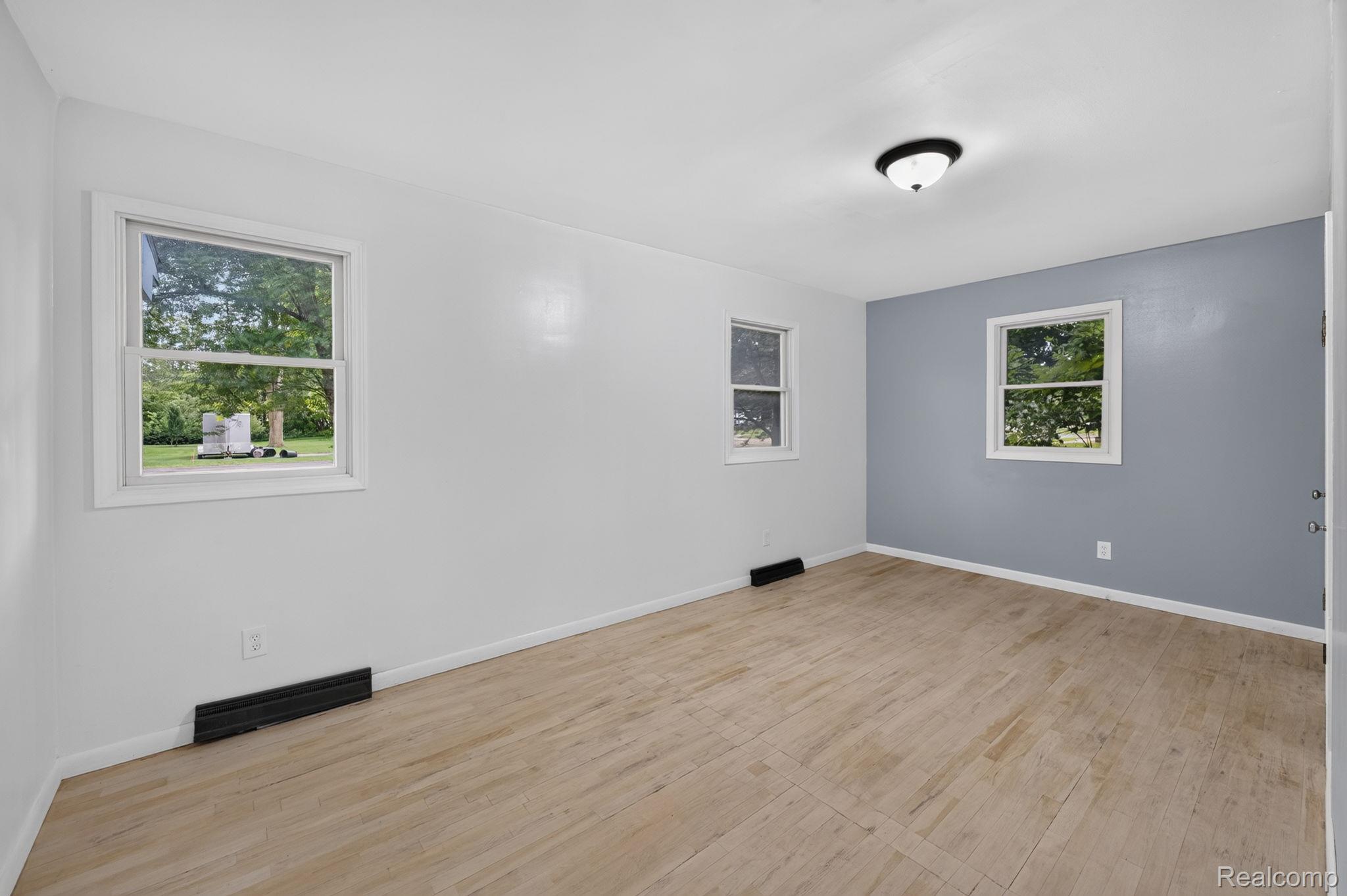 9288 Hilda Lane Flushing, MI 48433 - Photo 17 of 50 Room featuring wood-finish flooring, white walls, and a single accent wall in a muted blue hue