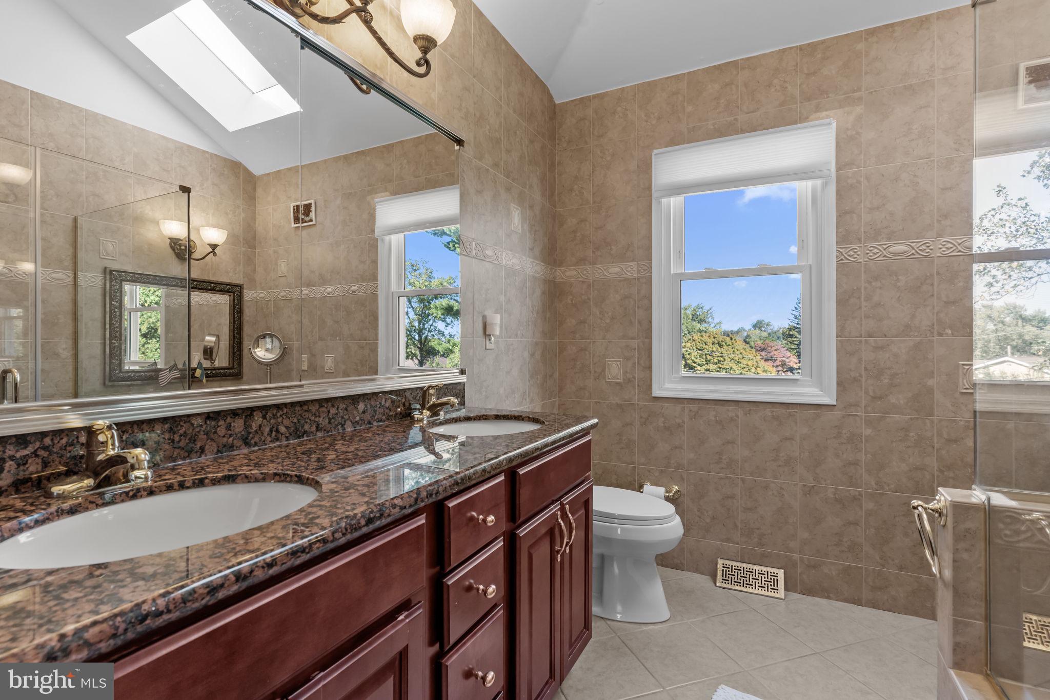 15 Roy Lane Huntingdon Valley, PA 19006 - Photo 21 of 45 a bathroom with a granite countertop sink a large mirror a toilet and a window