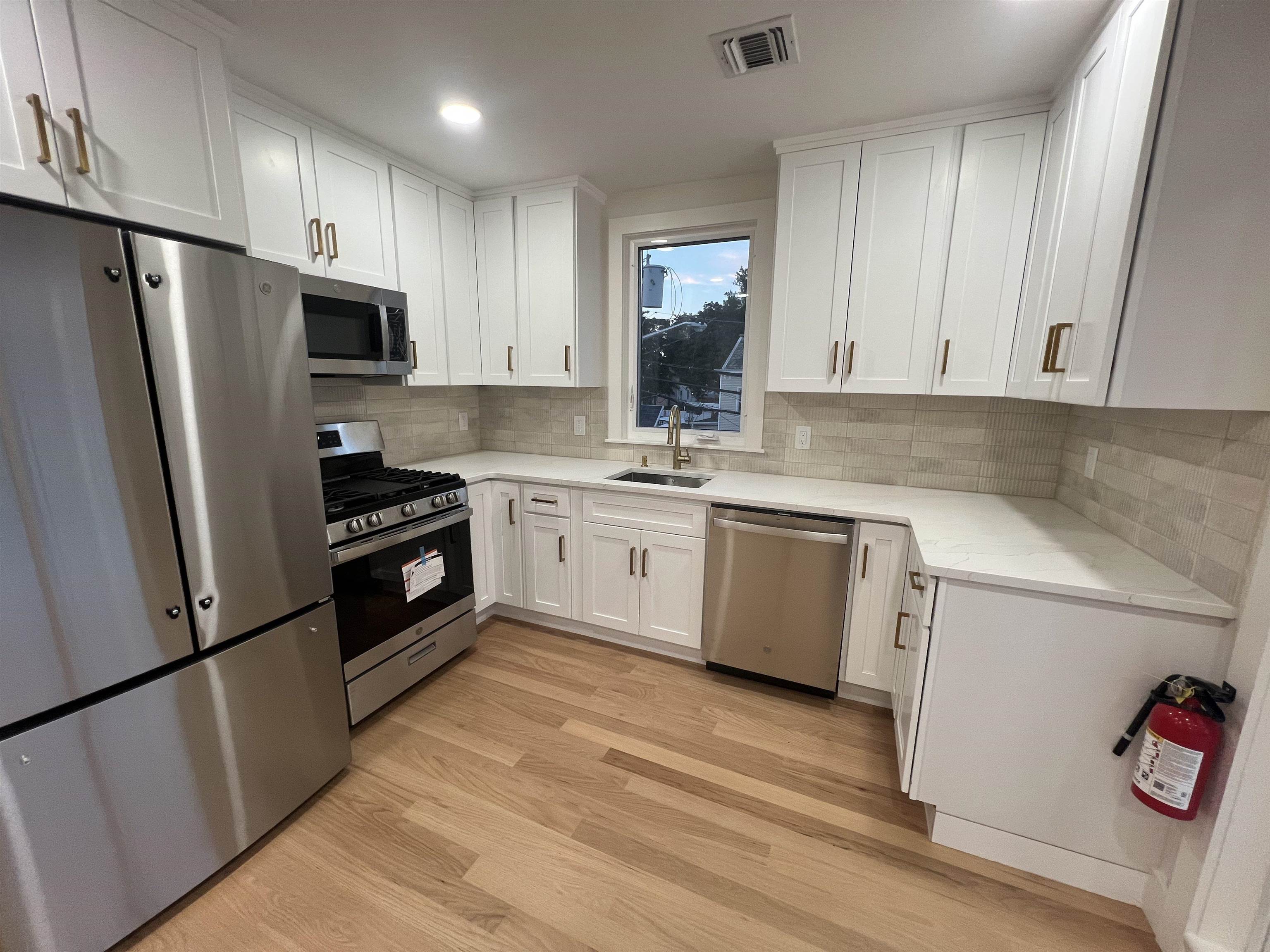210 Waldo Place, Unit 2 Englewood, NJ 07631 - Photo 5 of 23 a kitchen with a sink a refrigerator and a stove top oven