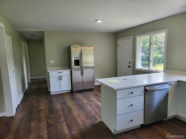 10089 Coldwater Road Flushing, MI 48433 - Photo 15 of 17 Contemporary kitchen featuring wood-finish flooring, white cabinetry, a stainless steel refrigerator, a stainless steel dishwasher, and light-toned countertops