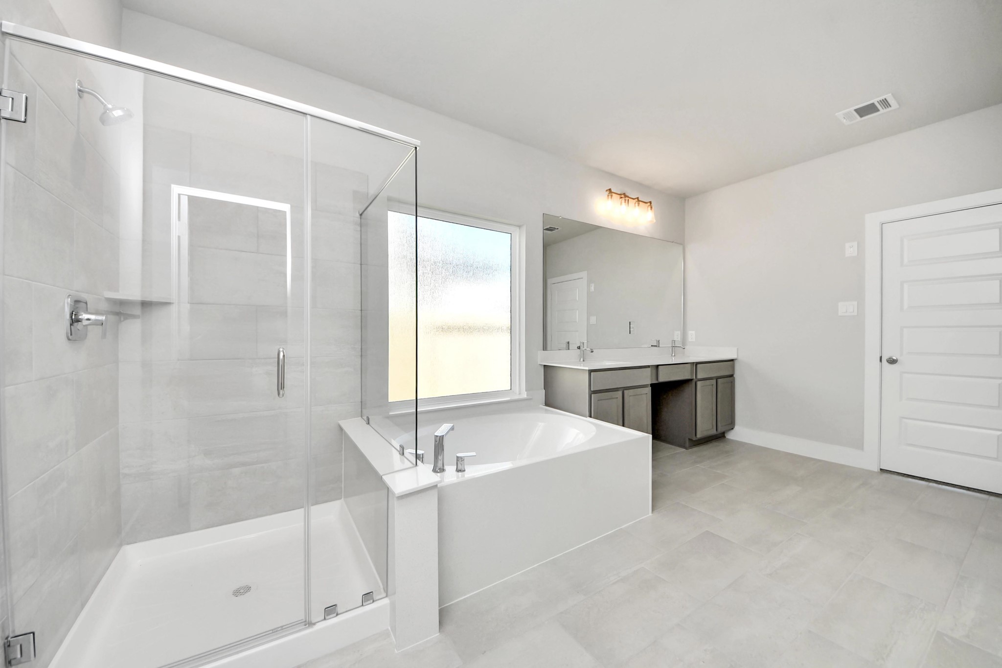 3042 Native Spg Drive Spring, TX 77373 - Photo 28 of 32 Escape to a spa-like oasis in this primary bathroom. Enjoy a walk-in shower with tile surround, a separate garden tub with custom detailing, and an elegant vanity featuring light countertops, modern hardware, and beautiful vanity lights. Experience luxury and relaxation in every detail. Sample photo of completed home with similar floor plan. Actual colors and selections may vary.