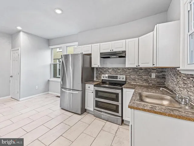 a kitchen with stainless steel appliances granite countertop a refrigerator a stove and a sink