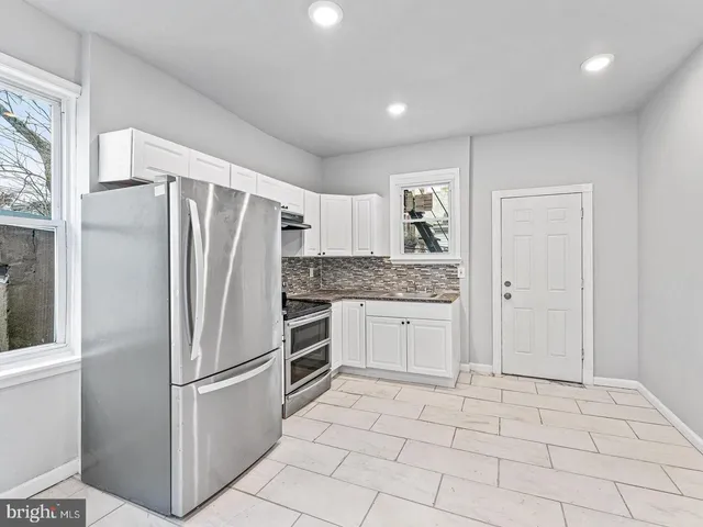 a kitchen with white cabinets and refrigerator