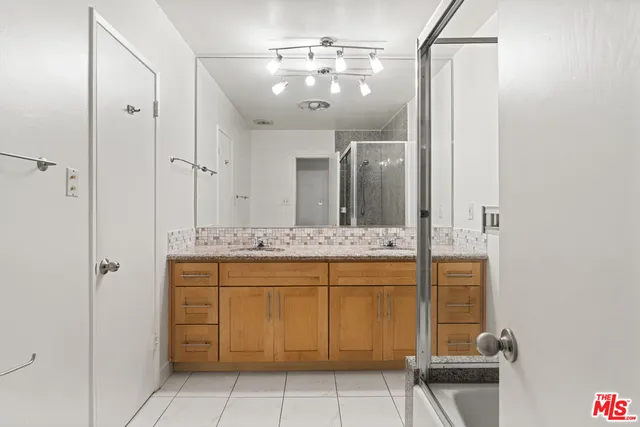 a bathroom with a granite countertop sink a mirror and shower