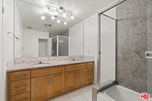 a bathroom with a granite countertop sink a mirror and a shower