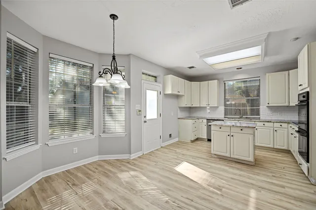 a kitchen with kitchen island granite countertop a stove a refrigerator a sink dishwasher a dining table and chairs with wooden floor