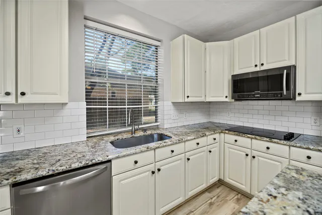 a kitchen with granite countertop cabinets stainless steel appliances a sink and window