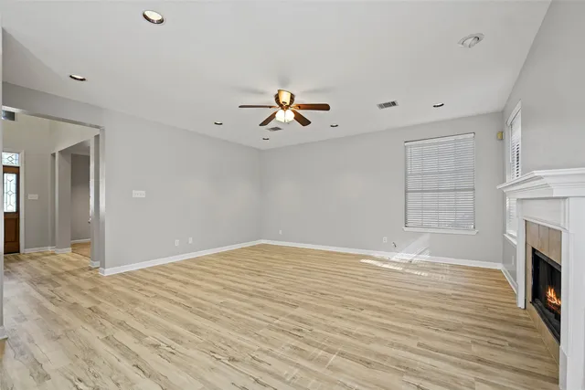 a view of empty room with fireplace and wooden floor