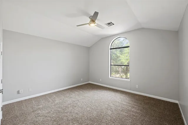 an empty room with window and chandelier fan