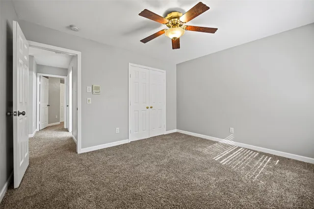 an empty room with closet and a chandelier fan