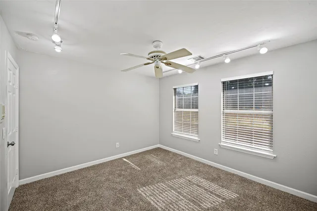 en empty room with windows and ceiling fan