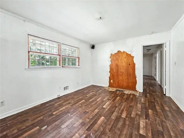 a view of an empty room with wooden floor and a window