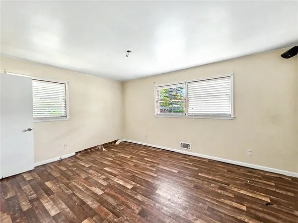 a view of a big room with wooden floor and windows