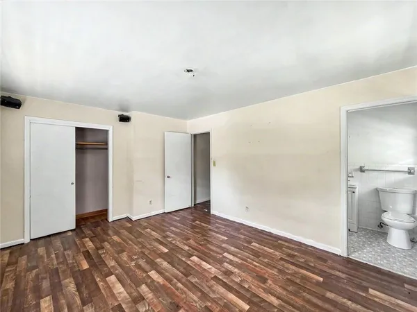 a view of a livingroom with wooden floor and a bathroom
