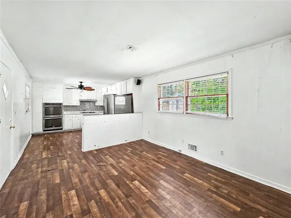 a view of a kitchen with wooden floor electronic appliances and windows