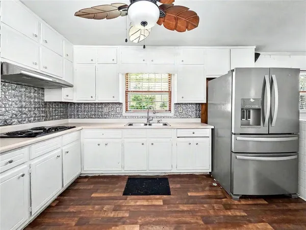 a kitchen with a sink stainless steel appliances a window and cabinets
