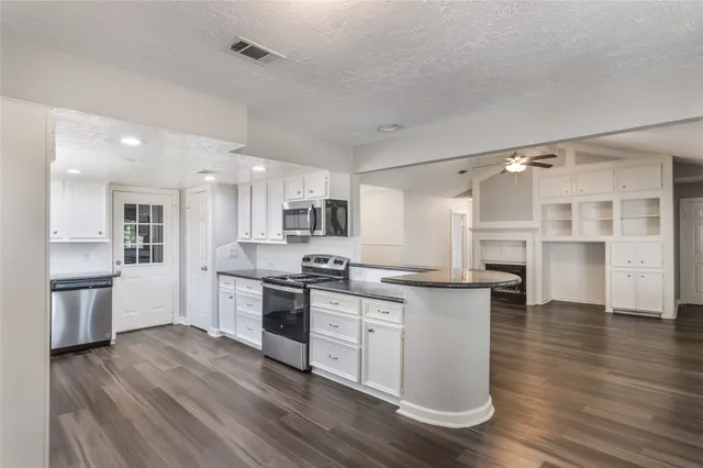 a kitchen with stainless steel appliances granite countertop a stove top oven a sink dishwasher and a refrigerator with wooden floor